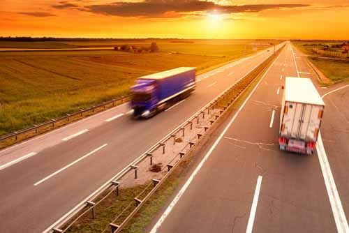 Two Freight Broker trucks pass each other on a highway